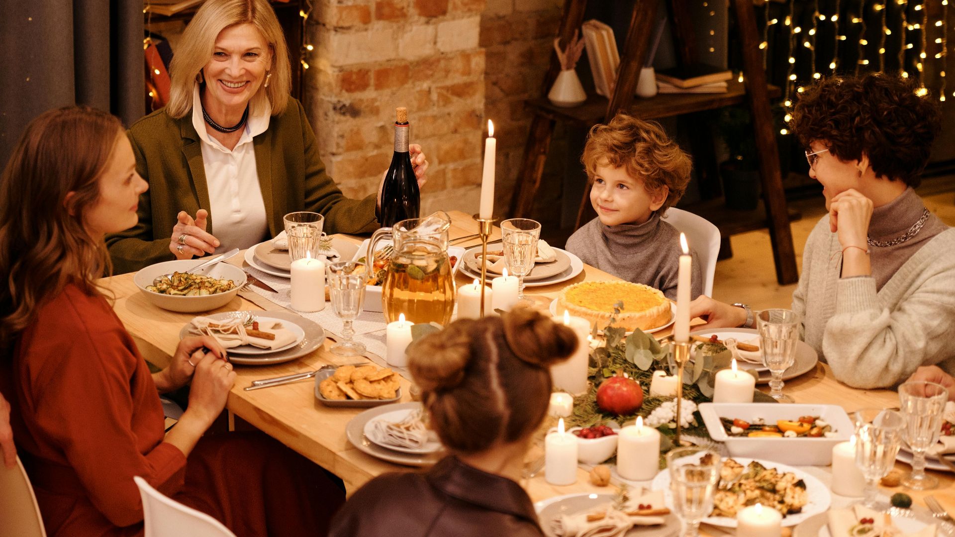 Warm family gathering enjoying Christmas dinner with festive decor and lights.