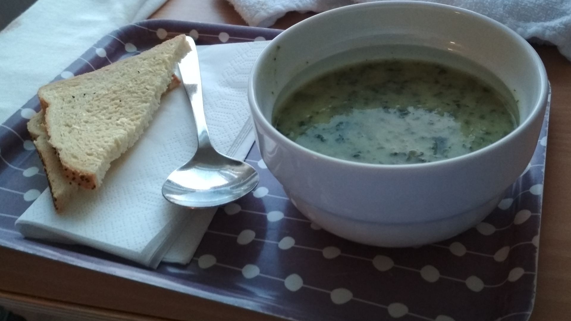 A bowl of broccoli soup with bread.