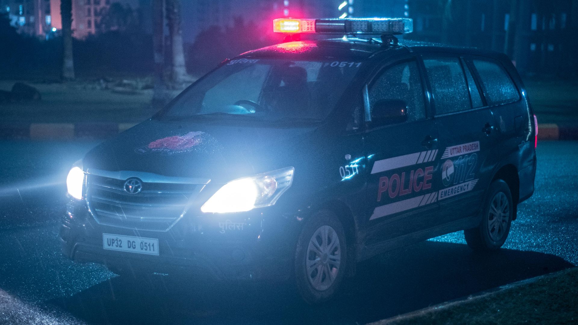 A Toyota police car patrols under city lights at night in Uttar Pradesh, India.