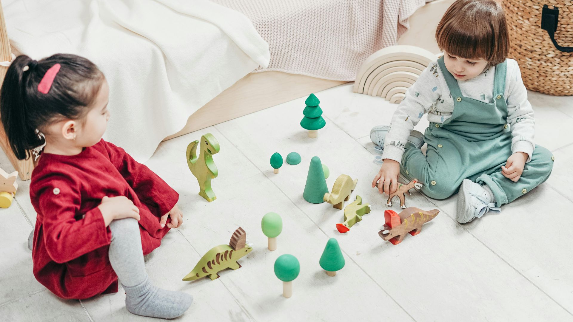 Two kids enjoying playtime with wooden toys in a cozy bedroom setting.