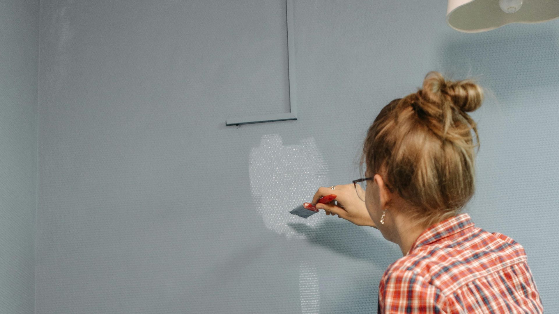 Two women painting a wall together, embodying teamwork and home improvement.