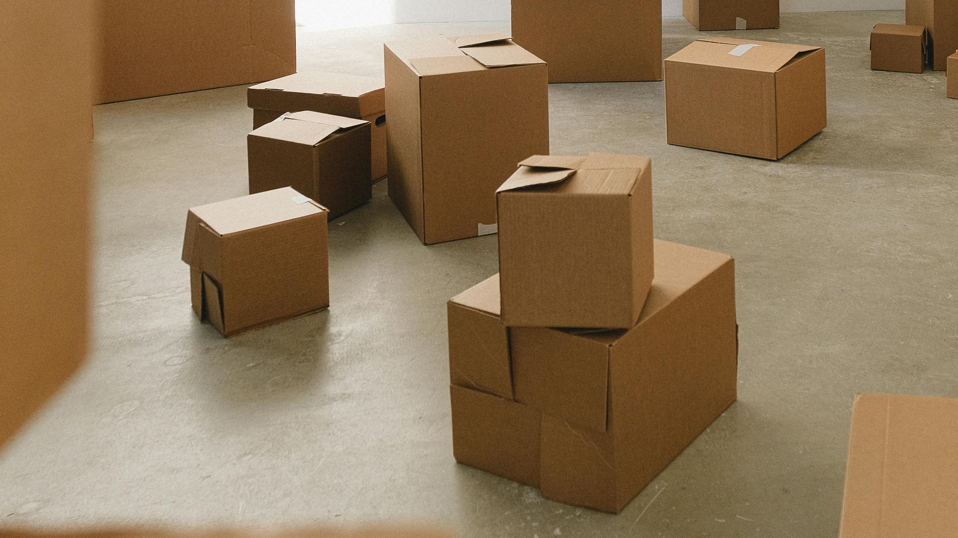 A man and woman playing in cardboard boxes during a move. Bright, indoor setting.