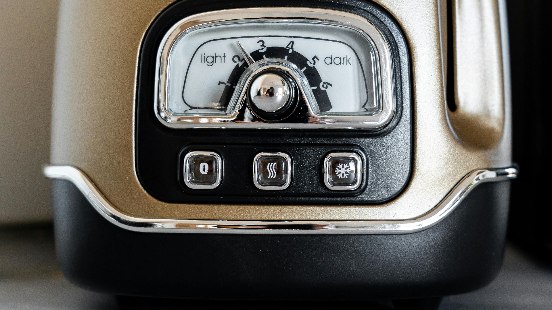A close-up view of a vintage-style toaster dial with light and dark settings in a kitchen.
