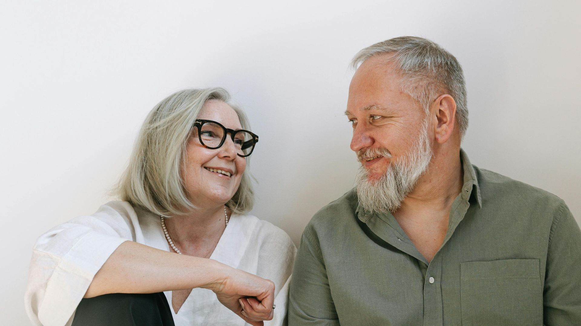 An elderly couple sharing a loving moment with smiles indoors.