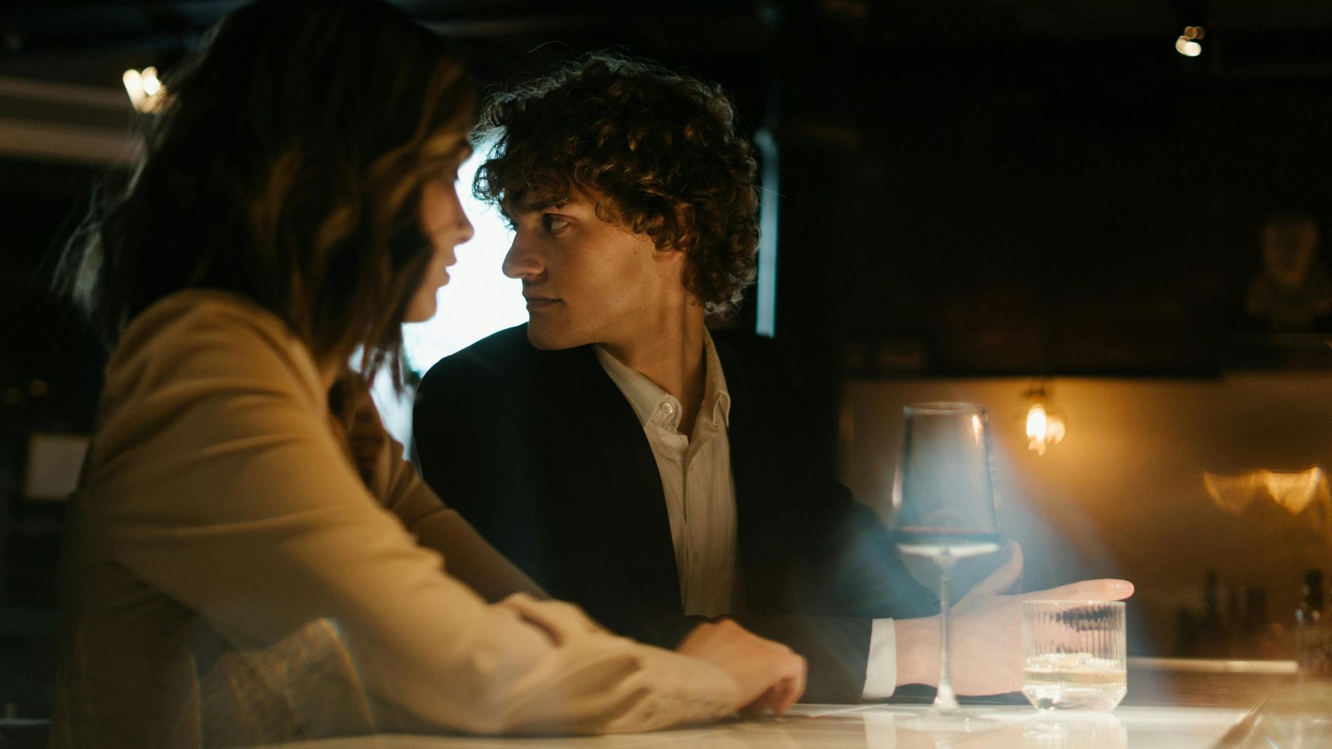 Young couple enjoying a romantic evening at an elegant bar. Warm lighting sets a cozy atmosphere.