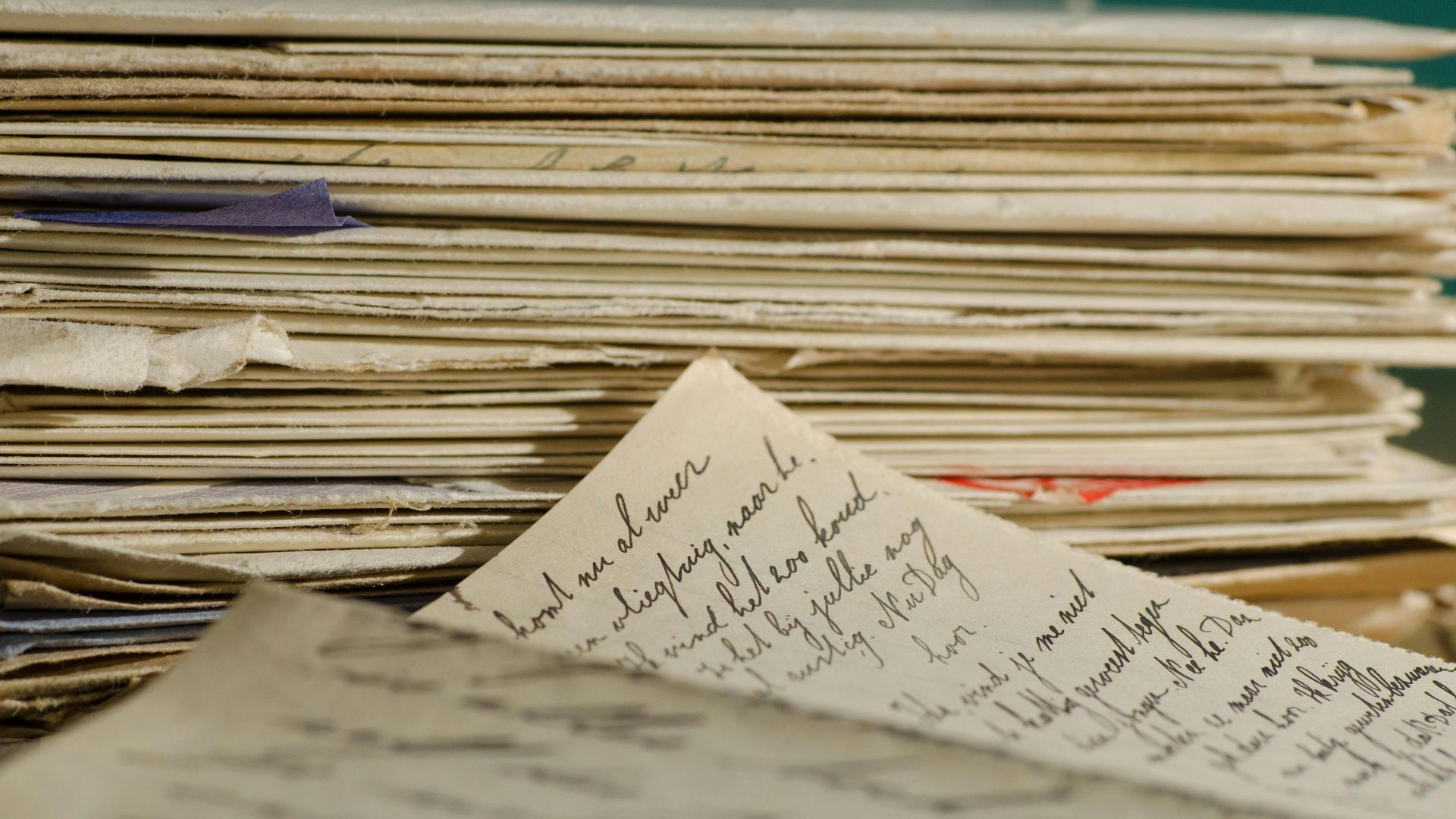Close-up image of handwritten letters and papers stacked together, conveying a vintage feel.
