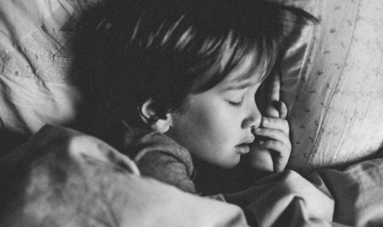 grayscale photo of girl sleeping on white pillow