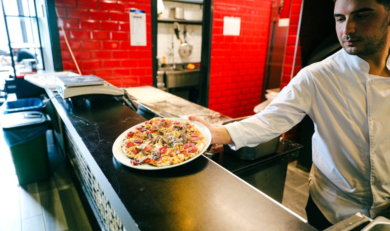 Chef Serving Freshly Made Pizza in Restaurant Kitchen