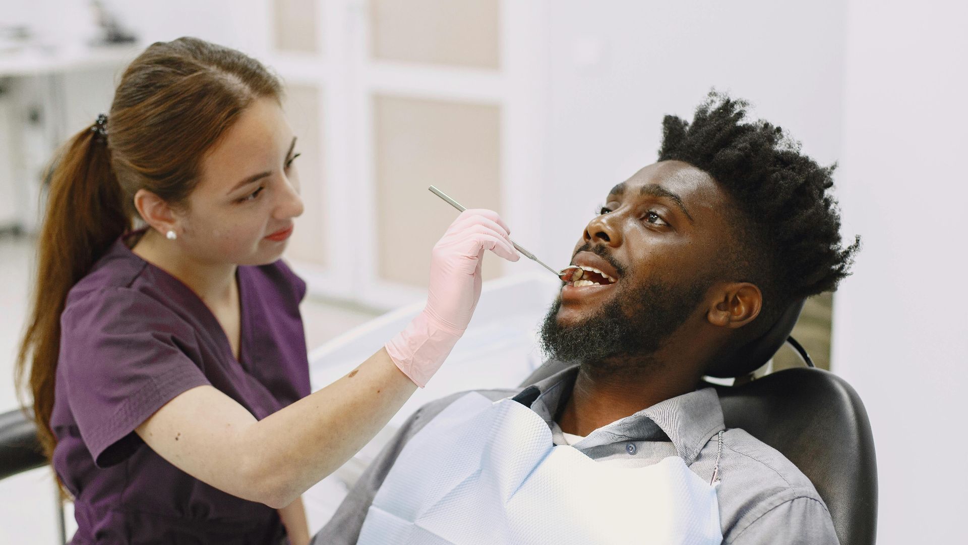 Female dentist examining a male patient in a modern dental clinic. Healthcare professionalism.