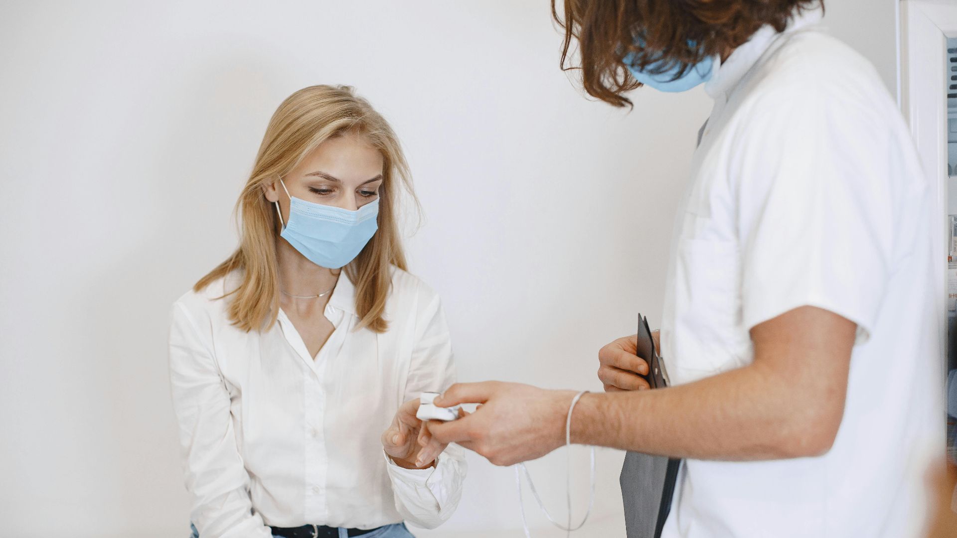 Doctor and patient wearing masks during an examination in a clinic setting.