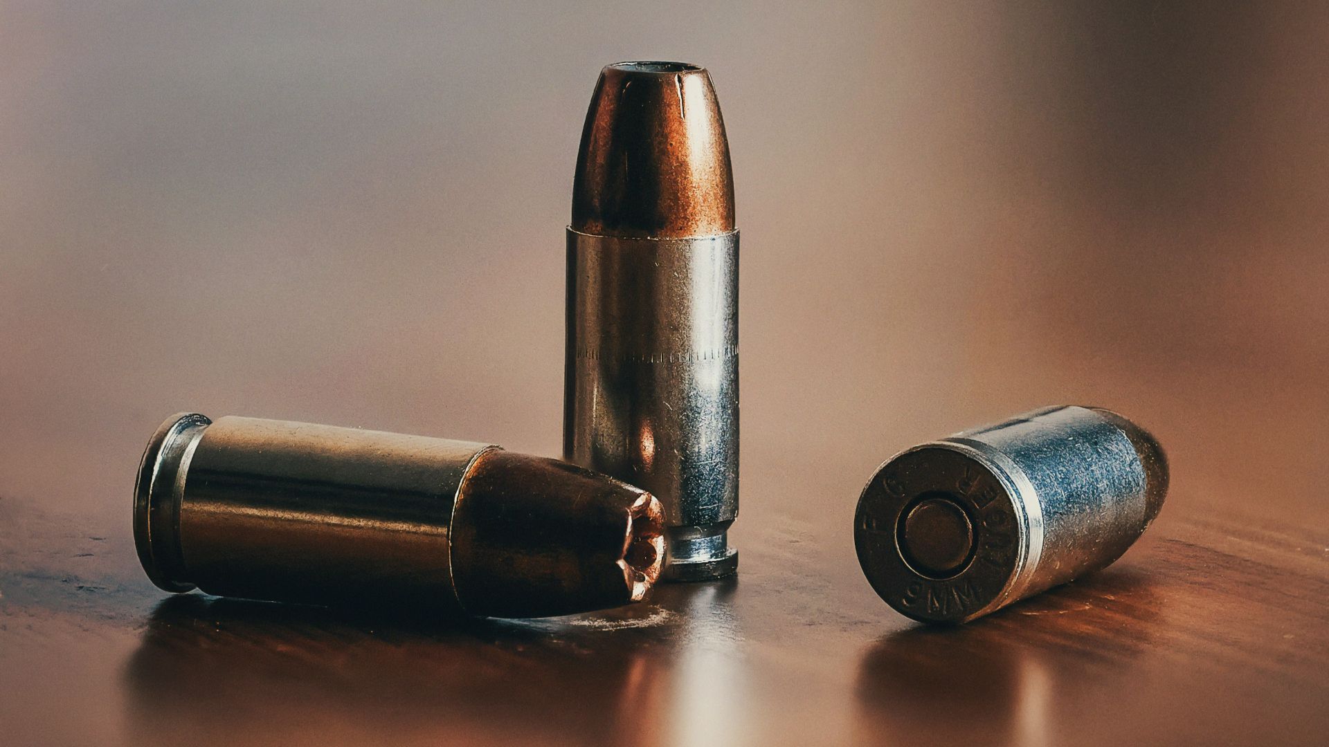 three gray bullets on brown surface