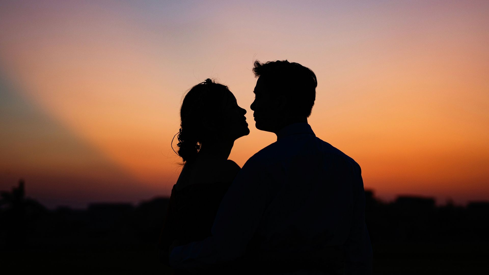 silhouette of man and woman kissing during sunset