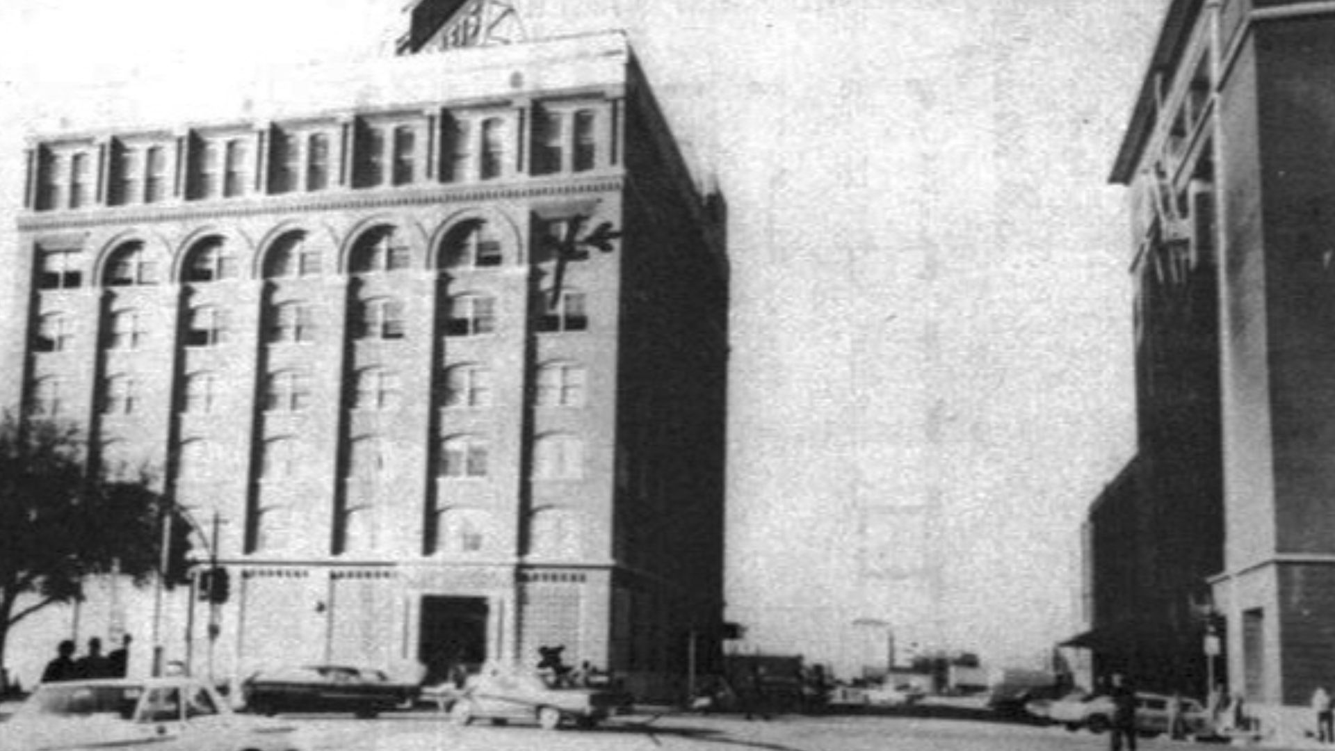 Texas School Book Depository from Houston Street. Mark on 6th floor. Originated from the report of the Warren Commission, a US Government report, WH Vol.16 p.957.