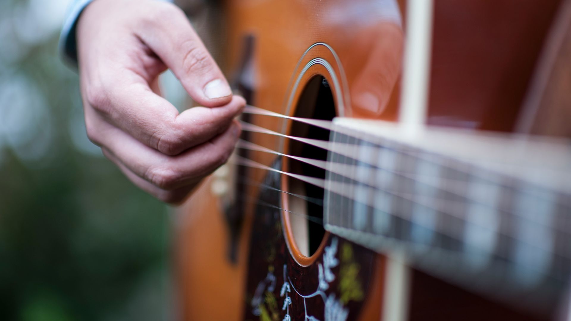 person playing brown acoustic guitar