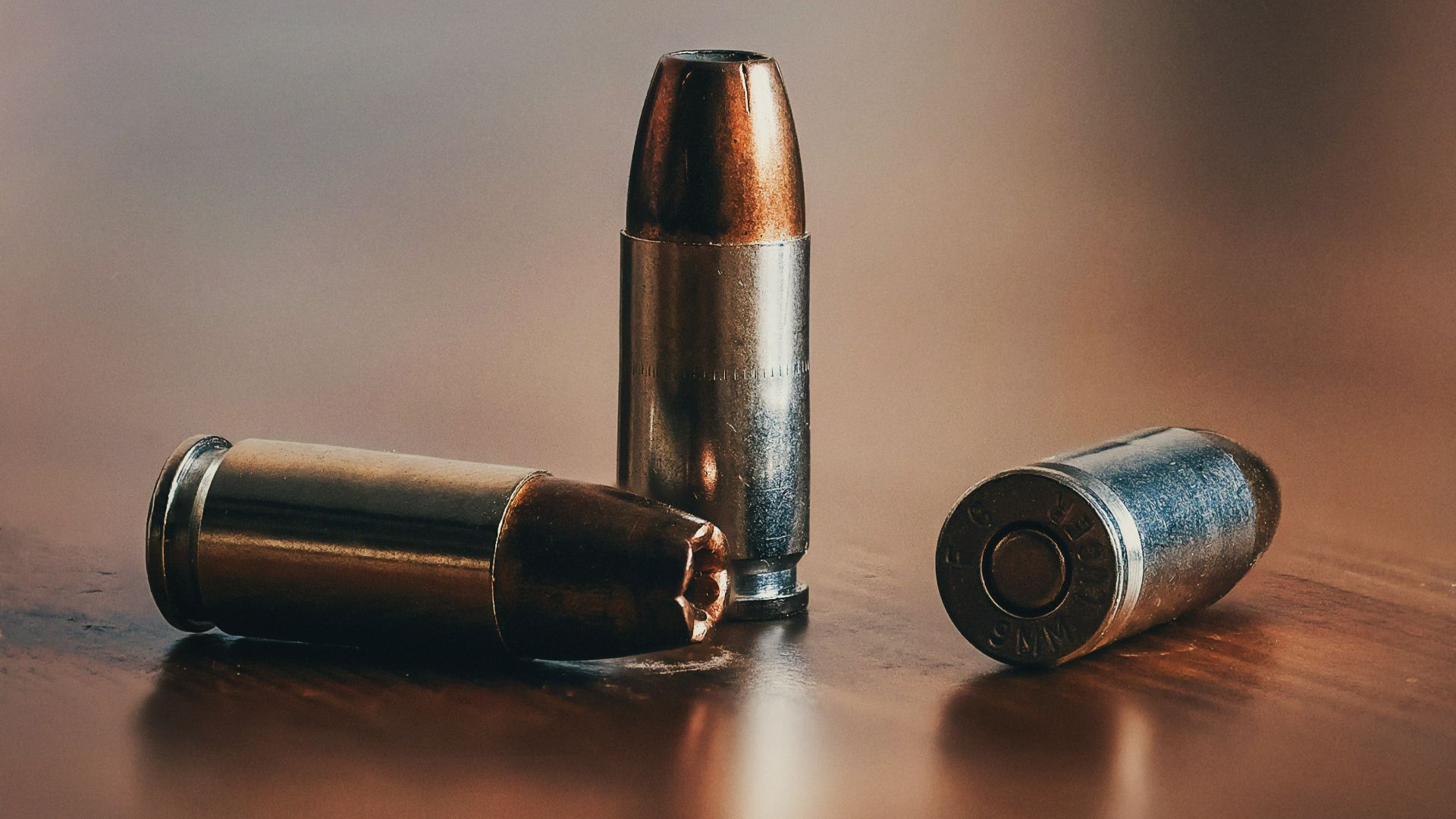 three gray bullets on brown surface