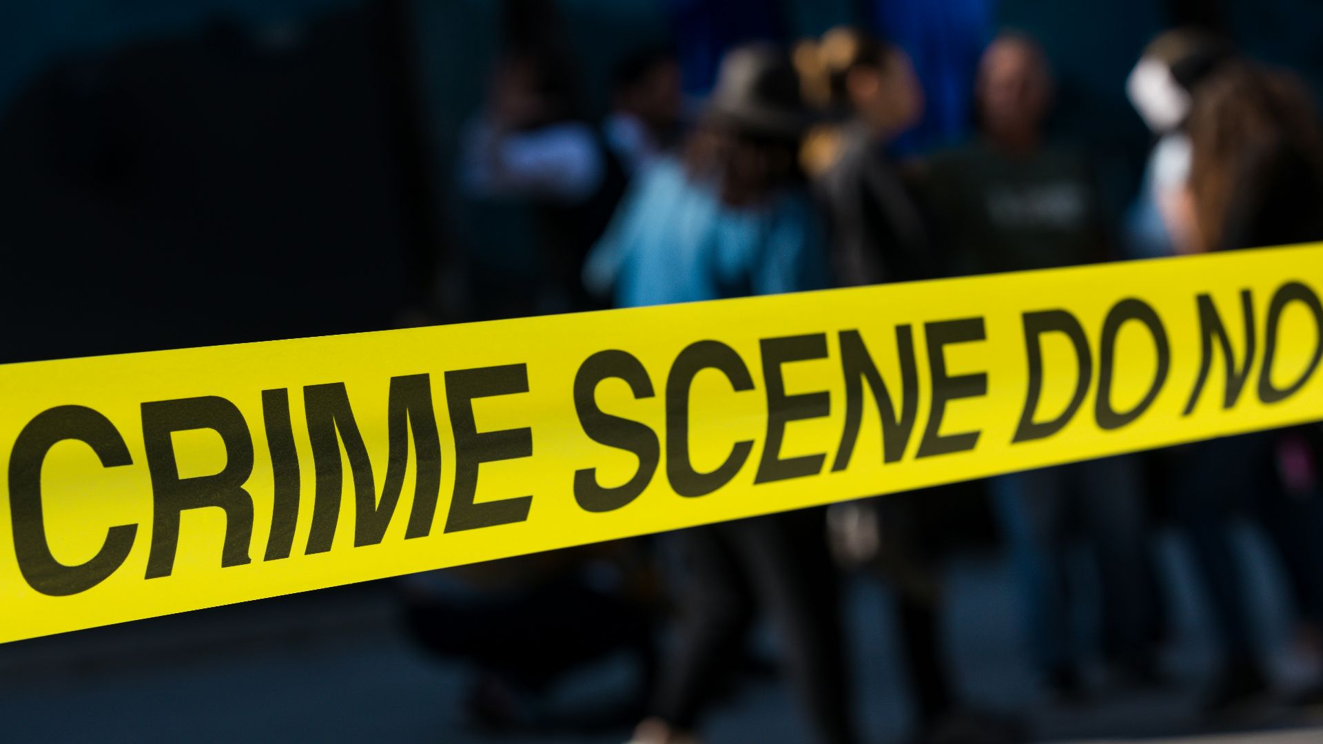 a group of people standing next to a yellow police line