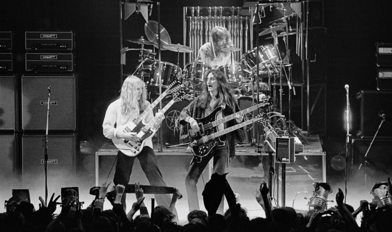 BIRMINGHAM, ENGLAND - 12th FEBRUARY: Guitarist Alex Lifeson, bassist Geddy Lee and (behind) drummer Neil Peart from Canadian progressive rock band Rush perform live on stage at the Odeon in Birmingham, England during their 'Farewell To Kings' tour on 12th February 1978.