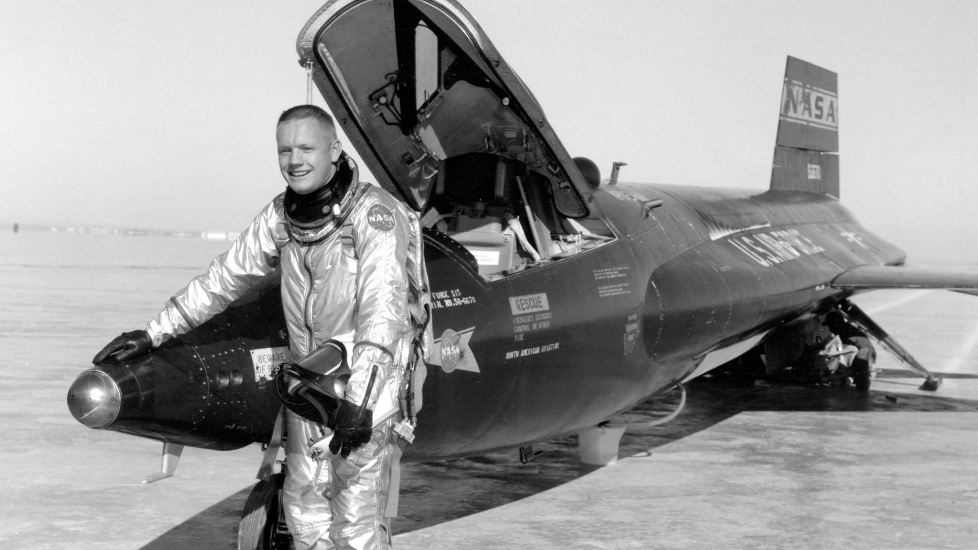 Dryden pilot Neil Armstrong is seen here next to the X-15 ship #1 (56-6670) after a research flight. Armstrong made his first X-15 flight on November 30, 1960, in the #1 X-15. He made his second flight on December 9, 1960, in the same aircraft. This was the first X-15 flight to use the ball nose, which provided accurate measurement of air speed and flow angle at supersonic and hypersonic speeds. The servo-actuated ball nose can be seen in this photo in front of Armstrong's right hand. The X-15 employed a non-standard landing gear. It had a nose gear with a wheel and tire, but the main landing consisted of skids mounted at the rear of the vehicle. In the photo, the left skid is visible, as are marks on the lakebed from both skids. Because of the skids, the rocket-powered aircraft could only land on a dry lakebed, not on a concrete runway.
