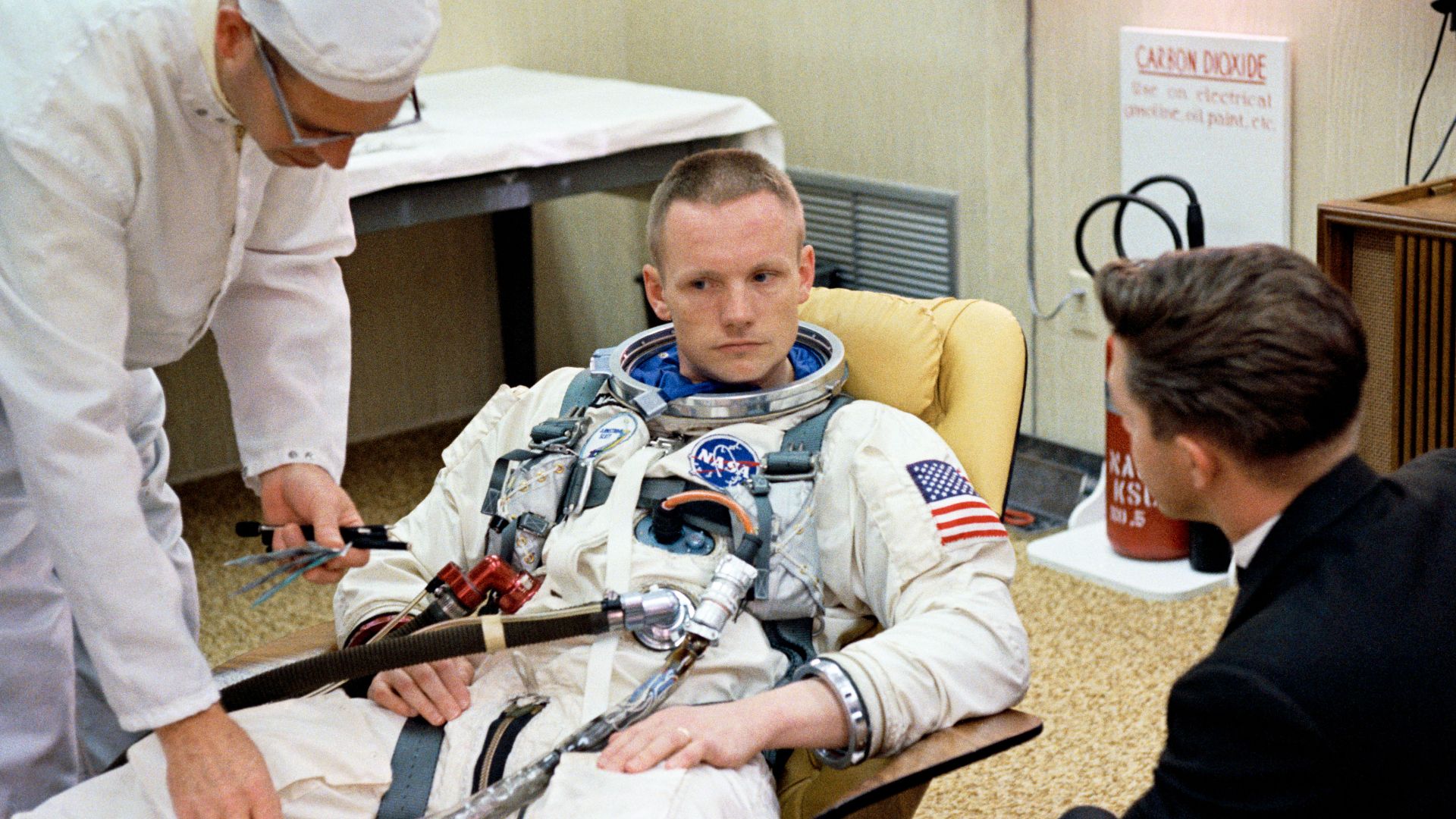 S66-24446 (16 March 1966) --- Astronaut Neil A. Armstrong, command pilot of the Gemini-8 spaceflight, sits in the Launch Complex 16 trailer during suiting up operations for the Gemini-8 mission. Suit technician Jim Garrepy assists. Photo credit: NASA