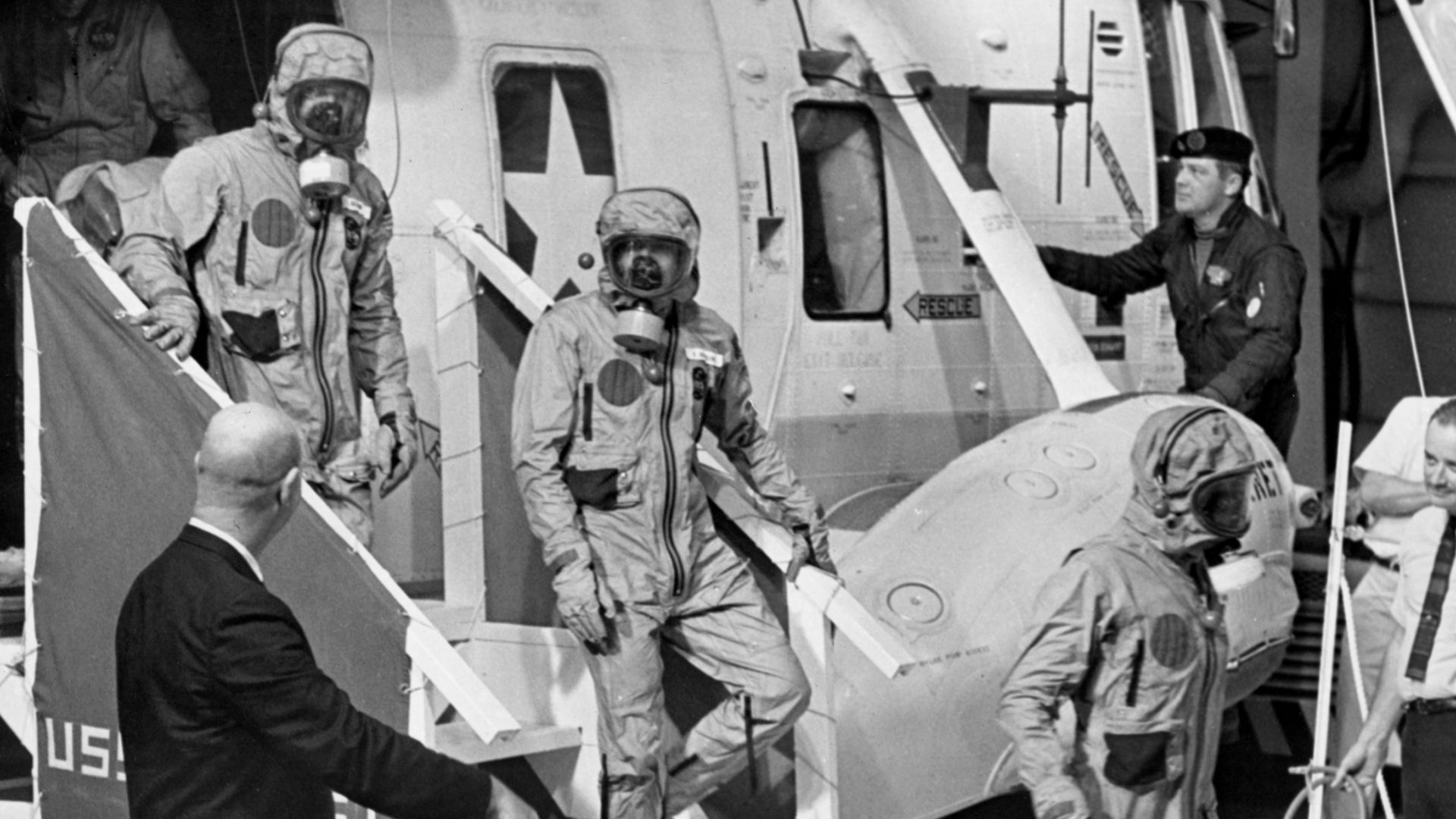 Apollo 11 astronauts in biohazard suits after recovery.