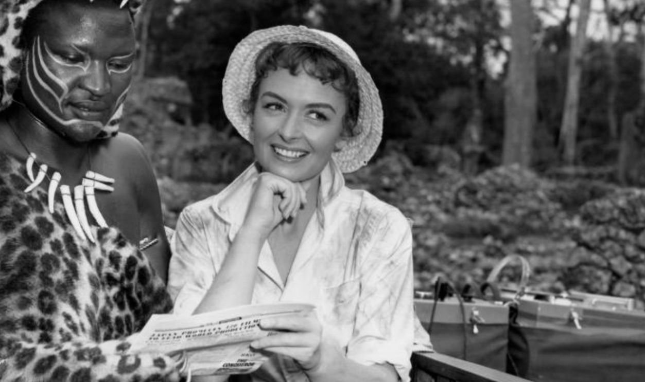 Publicity portrait of native African actor Bartholomew Sketch reading a newspaper alongside fellow American actor Donna Reed (1921-1986) on the set of the film 'Beyond Mombasa', 1956, United States. 