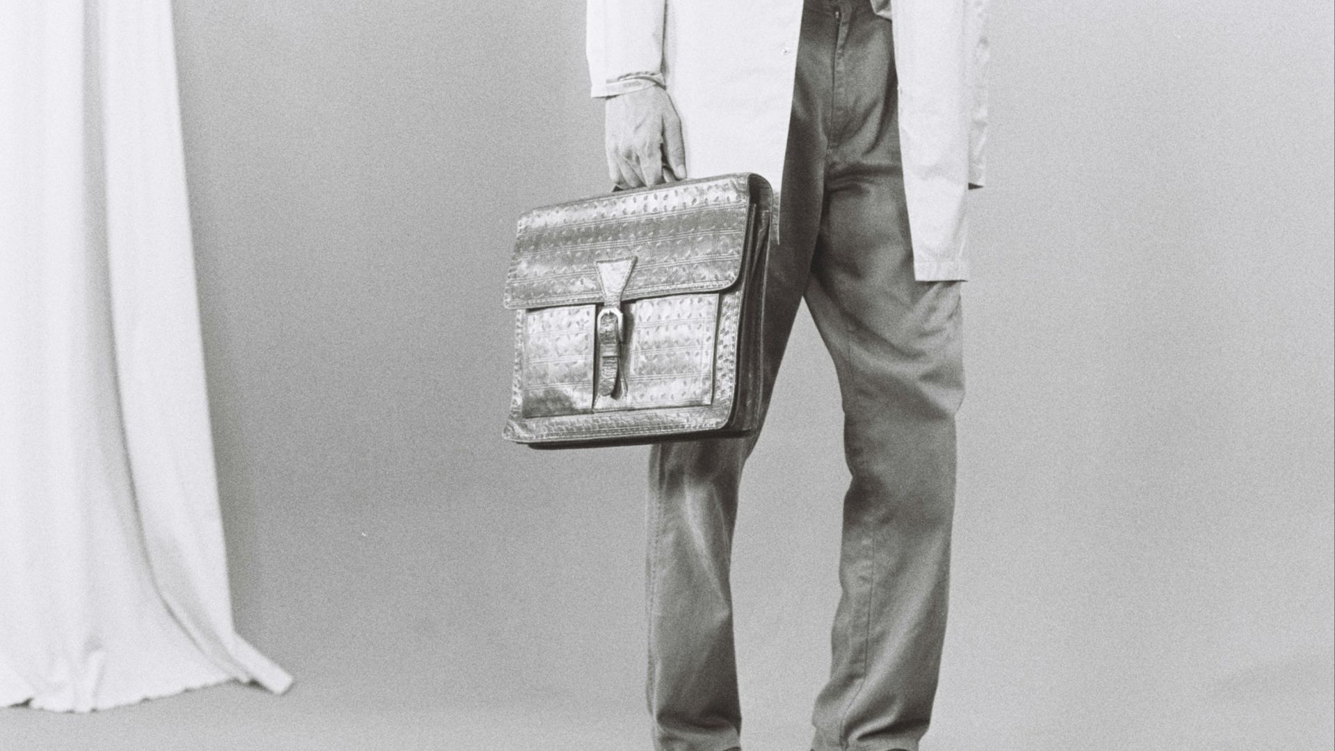 Man in lab coat holding briefcase on scale