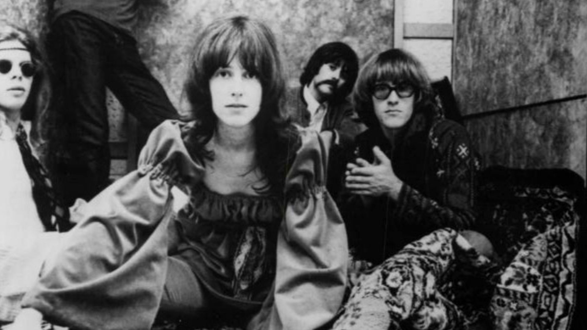 Publicity photo of Jefferson Airplane.  Clockwise from left: Jack Casady, Jorma Kaukonen, Marty Balin (seen in window frame), Spencer Dryden, Paul Kantner, Grace Slick.
