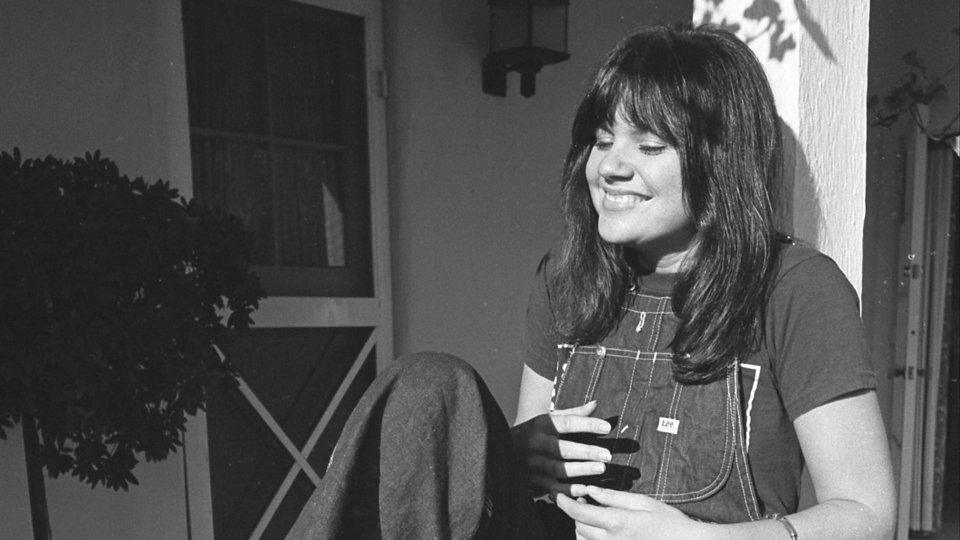 Linda Ronstadt reclining on porch railing in Los Angeles, California
