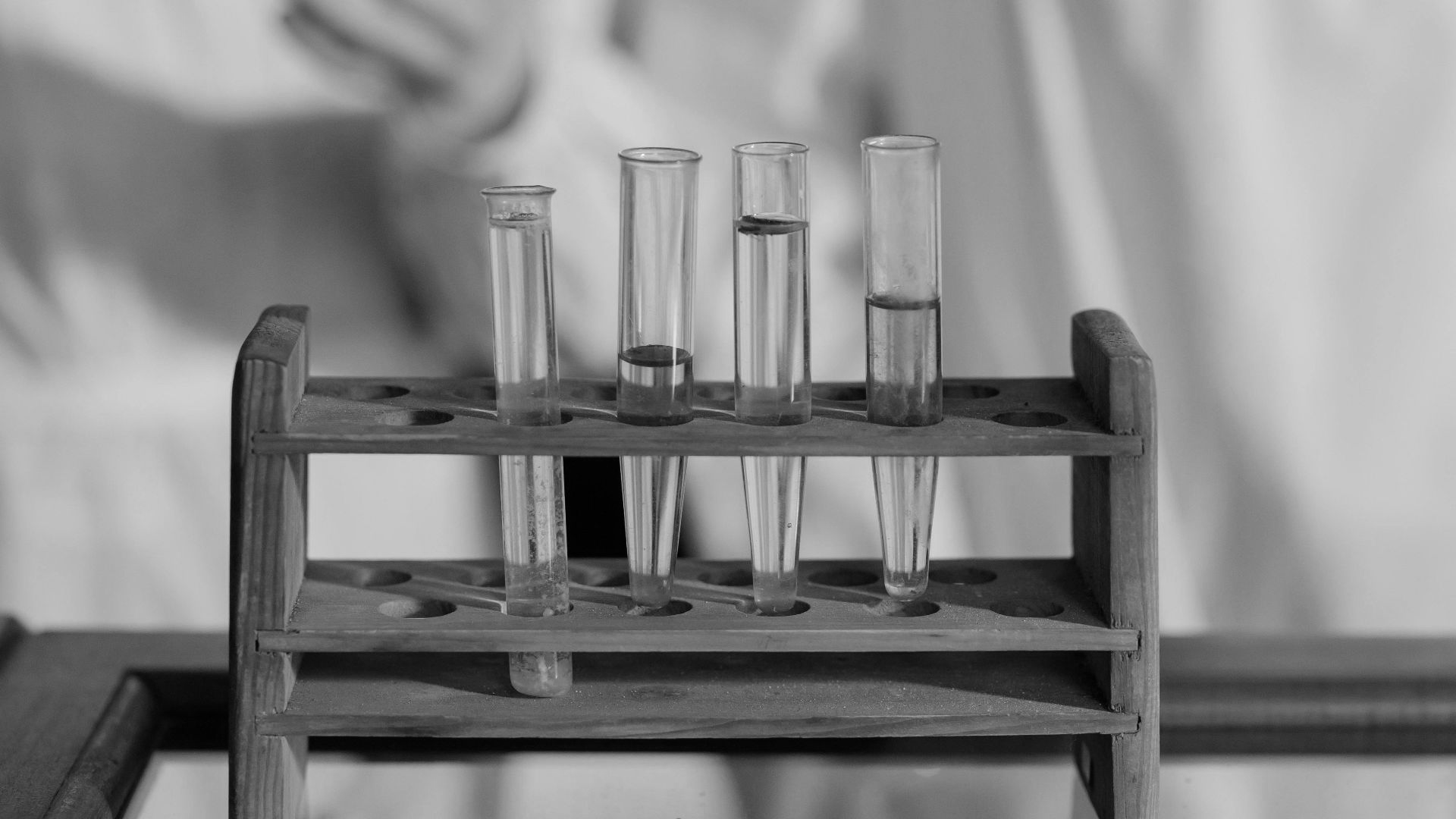 Chemists in lab coats examining various chemical solutions in test tubes with a focus on scientific research.