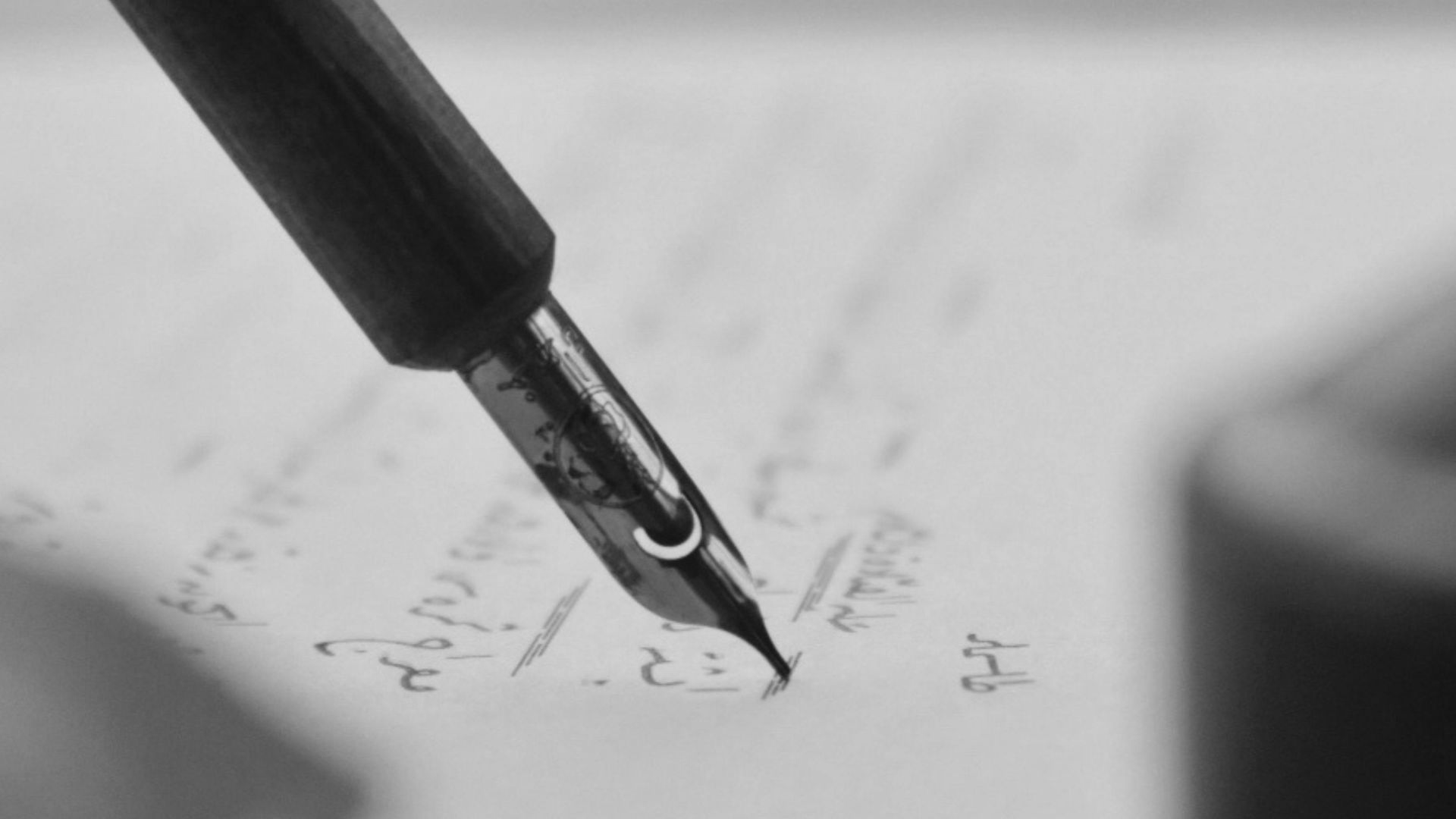 A detailed shot of a fountain pen writing elegant cursive script on paper.