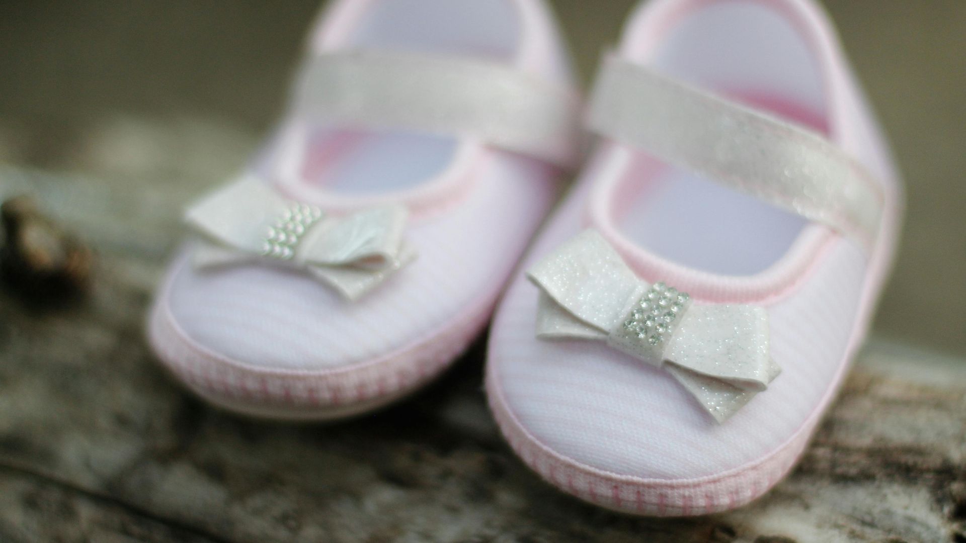 Close-up of adorable pink baby shoes with decorative bows, perfect for expecting parents.