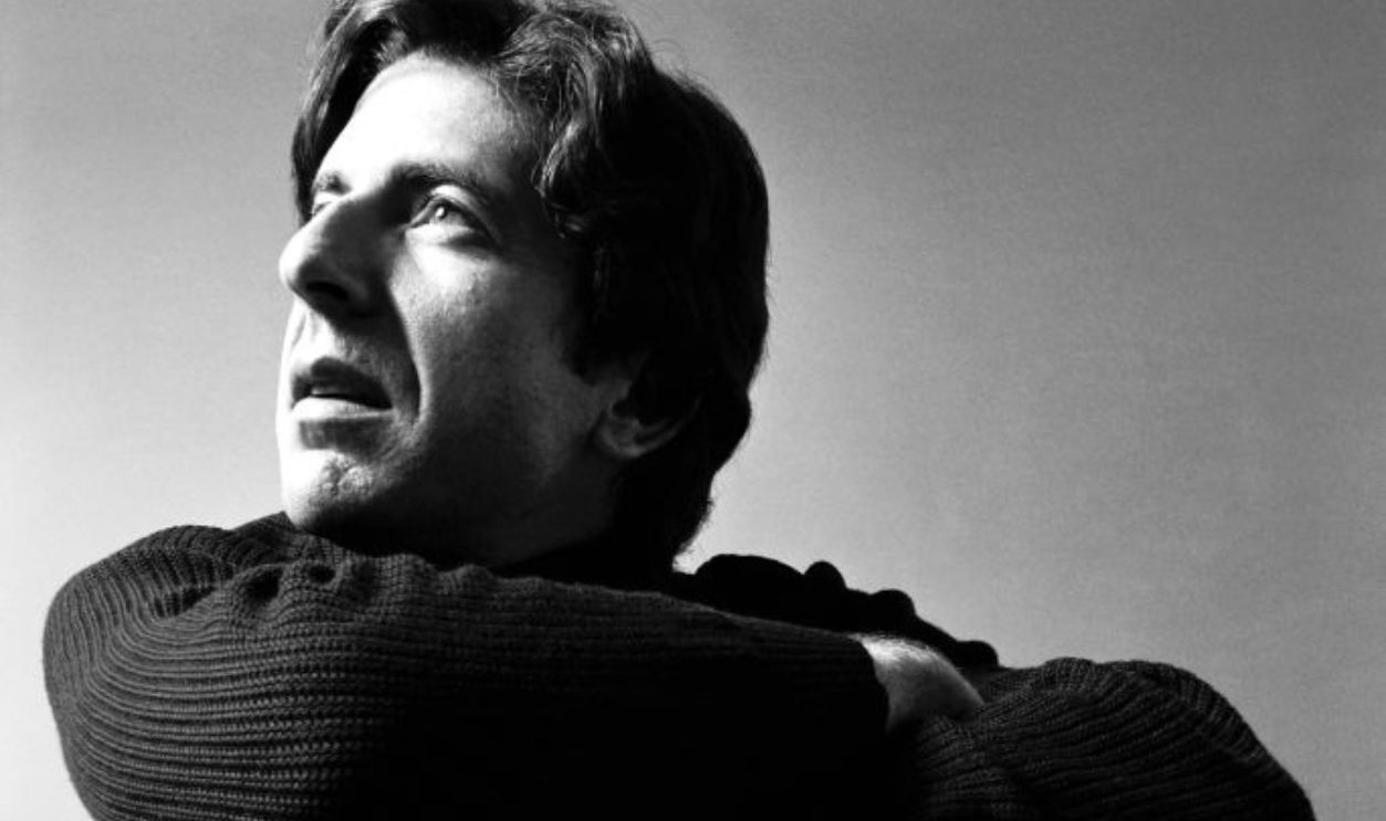 Portrait of Canadian poet, novelist, and musician Leonard Cohen (1934 - 2016), dressed in black, as he crouches down, his crossed arms resting on his knees, August 1967.