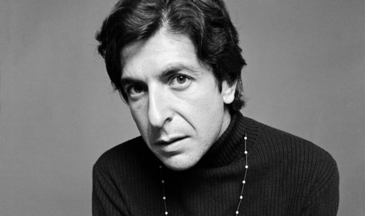 Portrait of Canadian poet, novelist, and singer-songwriter Leonard Cohen (1934 - 2016), dressed in black, as he holds a cigarette in one hand and, in the other, a notebook, pen, and package of cigarettes, August 1967.