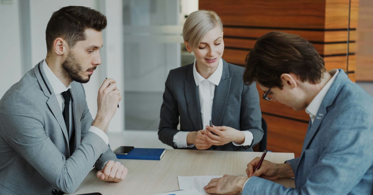 Business people signing a contract at a table.