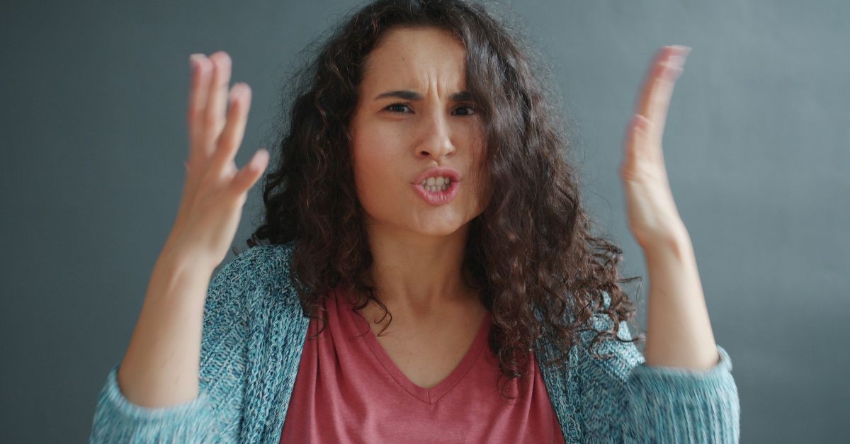 Woman with curly hair looking angry and frustrated.