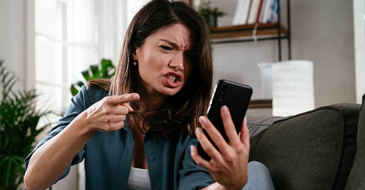 Sad woman sitting on the couch, using the phone.
