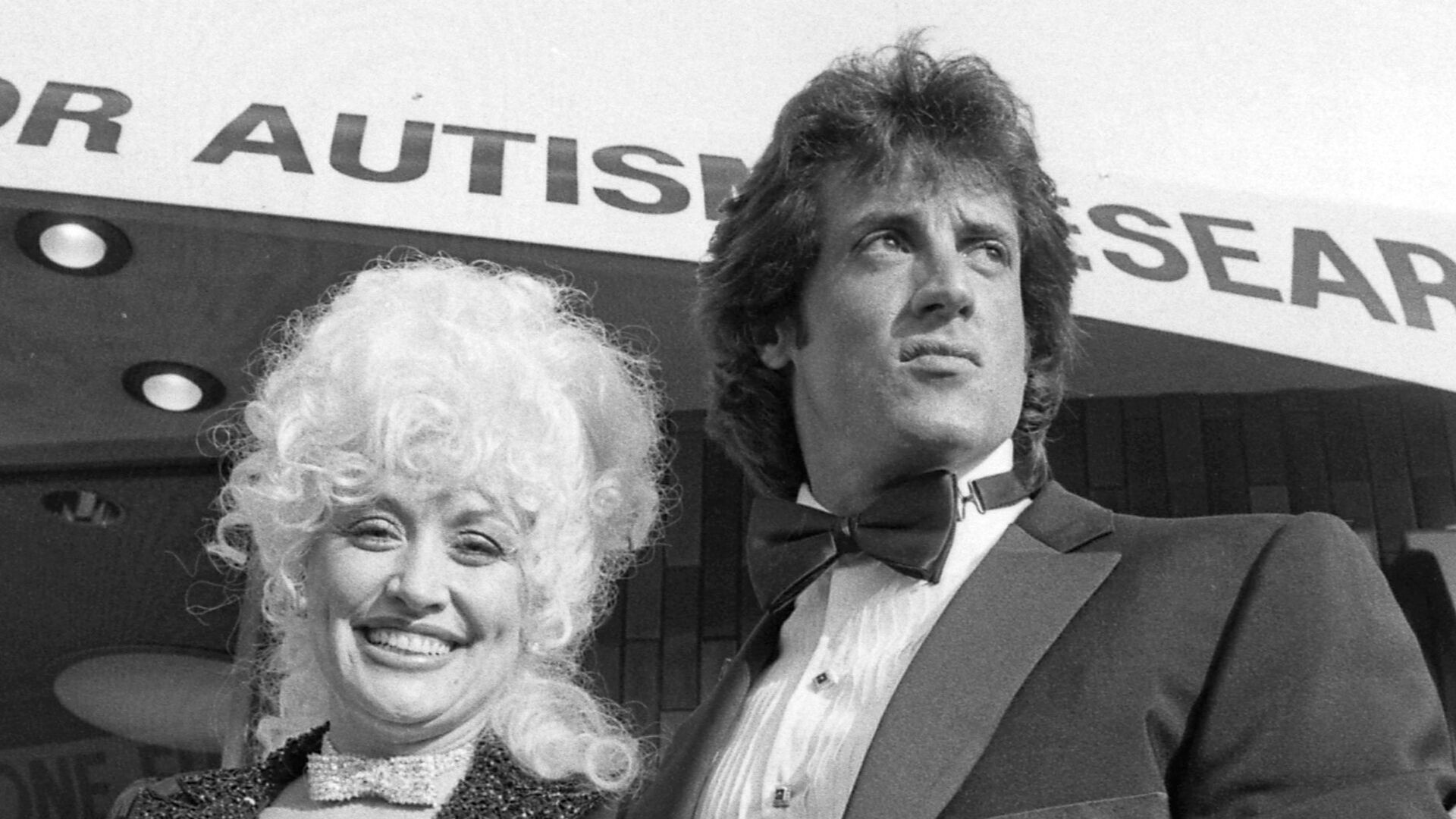 Dolly Parton and Sylvester Stallone arriving at benefit showing of their motion picture Rhinestone. Proceeds went to Los Angeles Chapter of the National Society for Children and Adults With Autism.
