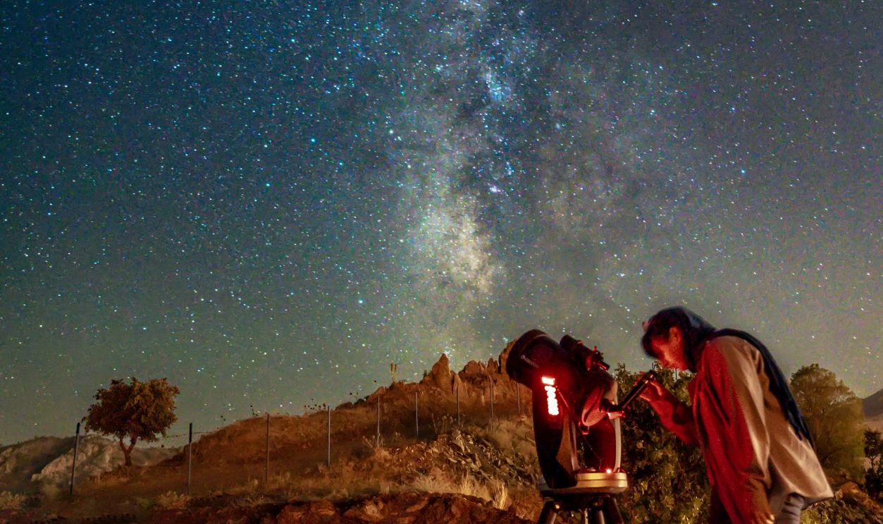 Woman with Telescope under Clear Night Sky with Stars