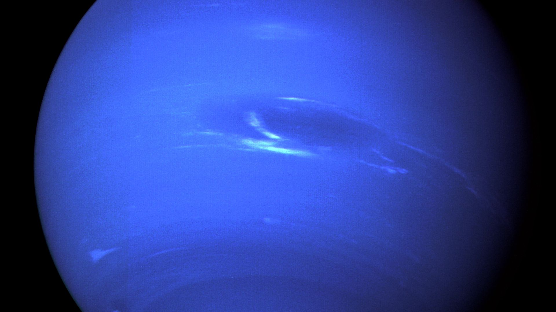 This enhanced-color picture of Neptune was produced from the last whole planet images taken through the green and orange filters on the Voyager 2 narrow angle camera. The images were taken at a range of 4.4 million miles from the planet, 4 days and 20 hours before closest approach in August 1989.The picture shows the Great Dark Spot and its companion bright smudge; on the west limb the fast moving bright feature called Scooter and the little dark spot are visible. These clouds were seen to persist for as long as Voyager's cameras could resolve them. North of these, a bright cloud band similar to the south polar streak may be seen.