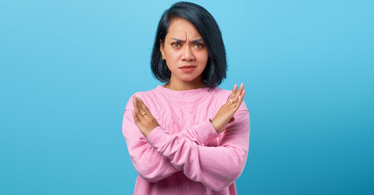 a woman in a pink sweater is holding her hands together