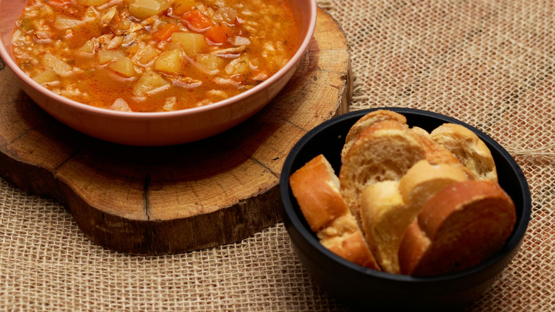 Warm vegetable soup and bread served on rustic surface, perfect for cozy meals.