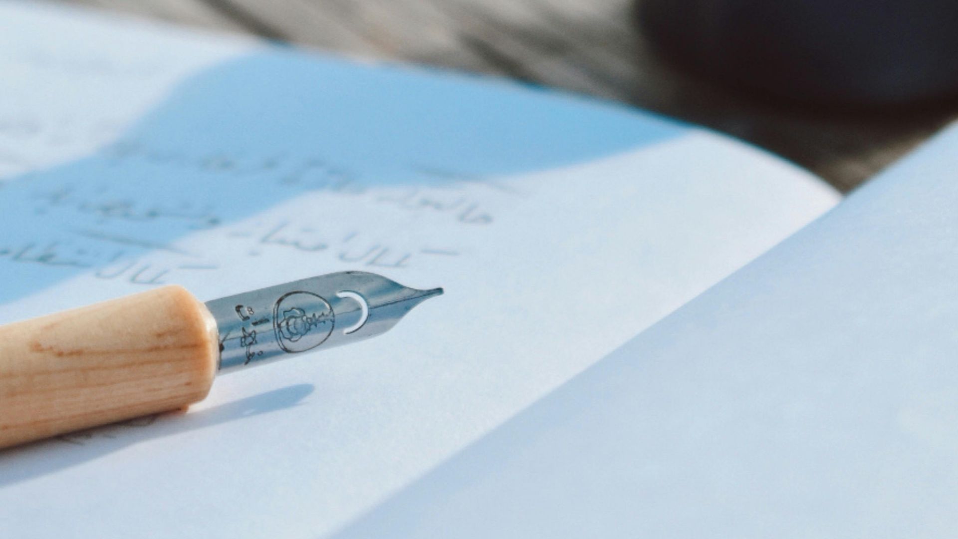 Close-up of a fountain pen and ink bottle outdoors on a wooden table.