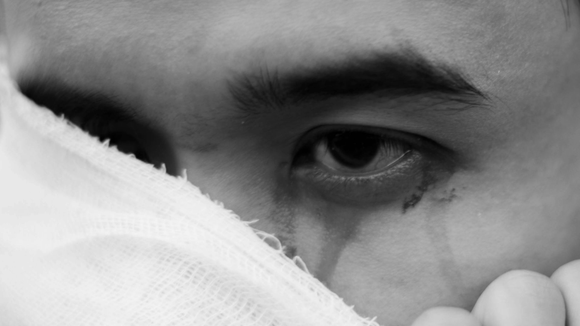 Close-up black and white image expressing emotion through eyes and gauze bandage.