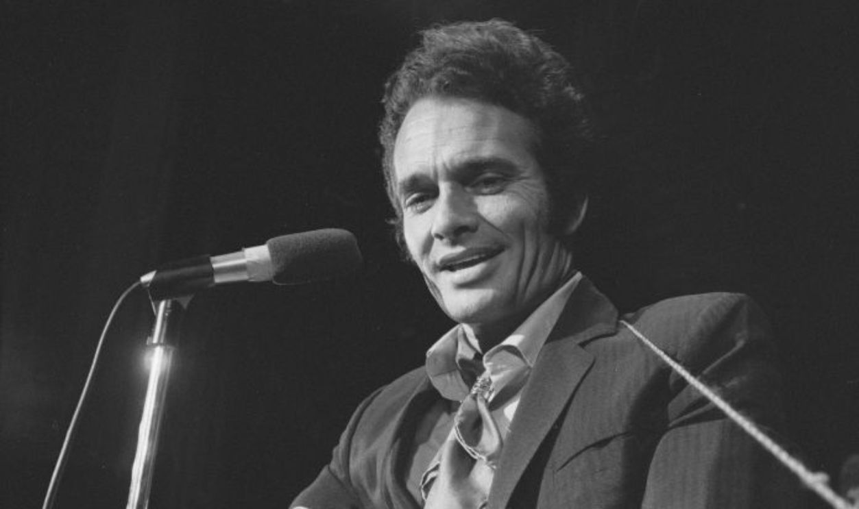 American country music performer Merle Haggard smiles as he plays an acoustic guitar, 1970.