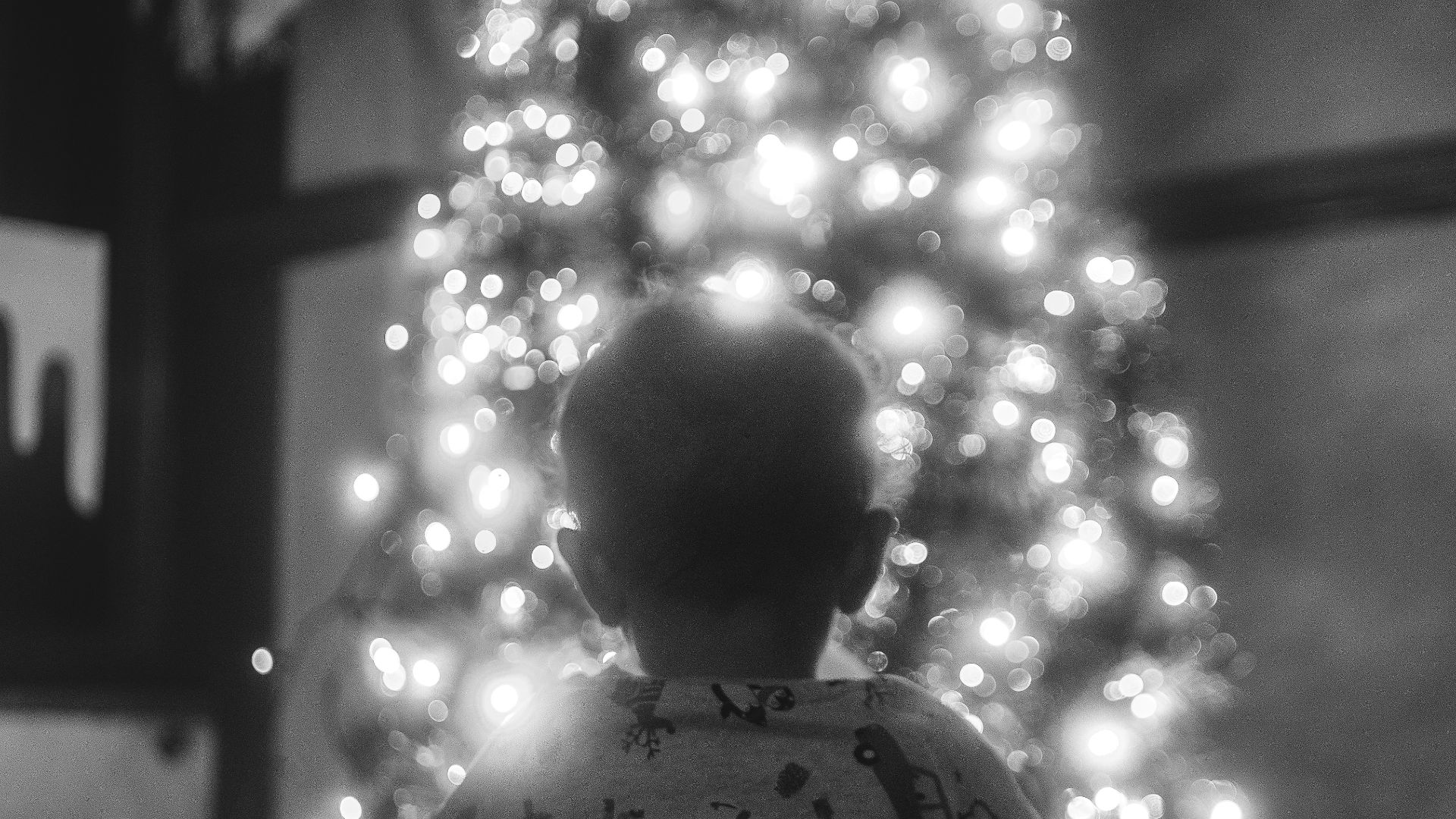 a little boy standing in front of a christmas tree