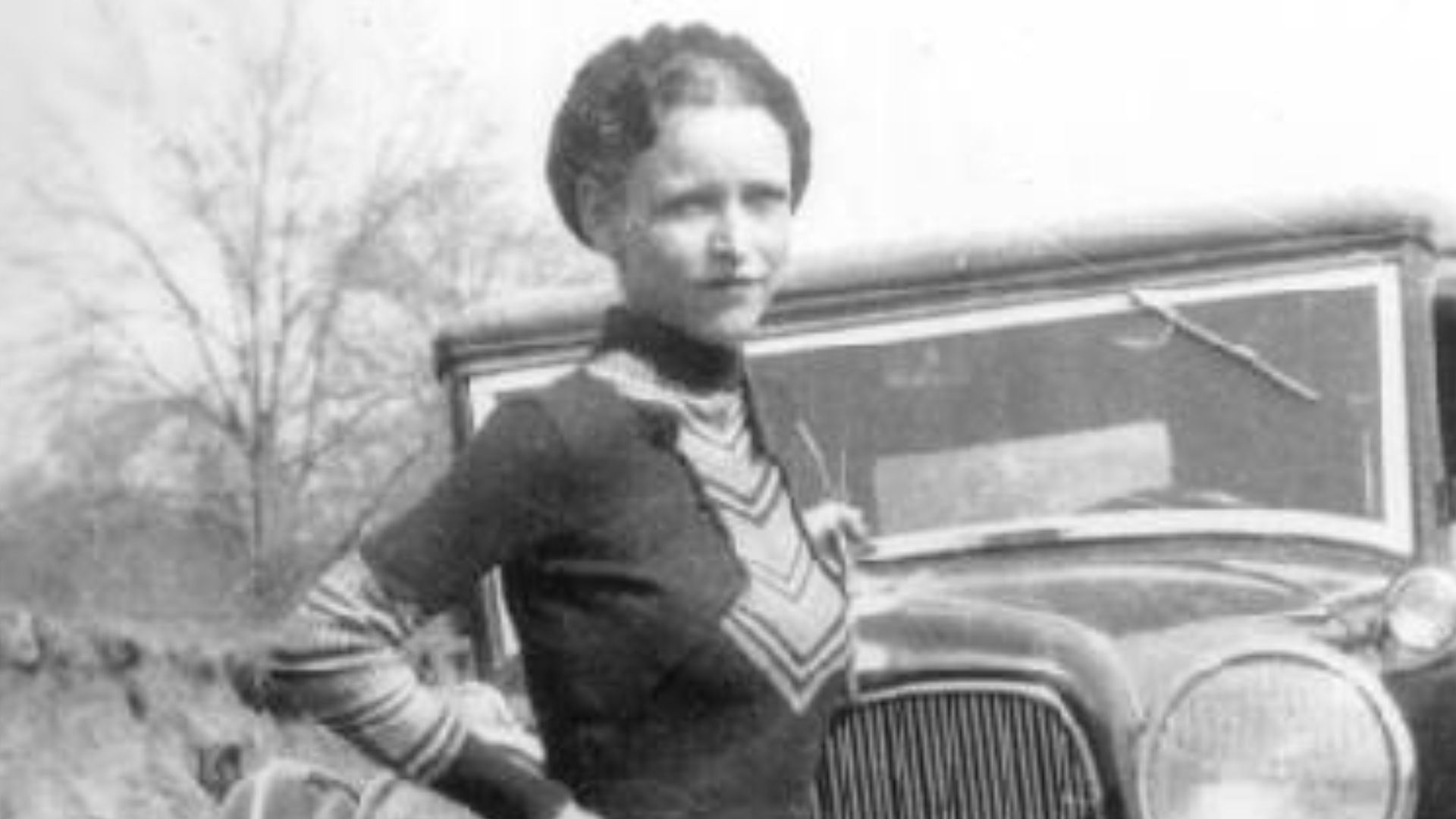 Bonnie Parker from Bonnie and Clyde standing in front of a Ford Model 18 (aka Ford V-8).