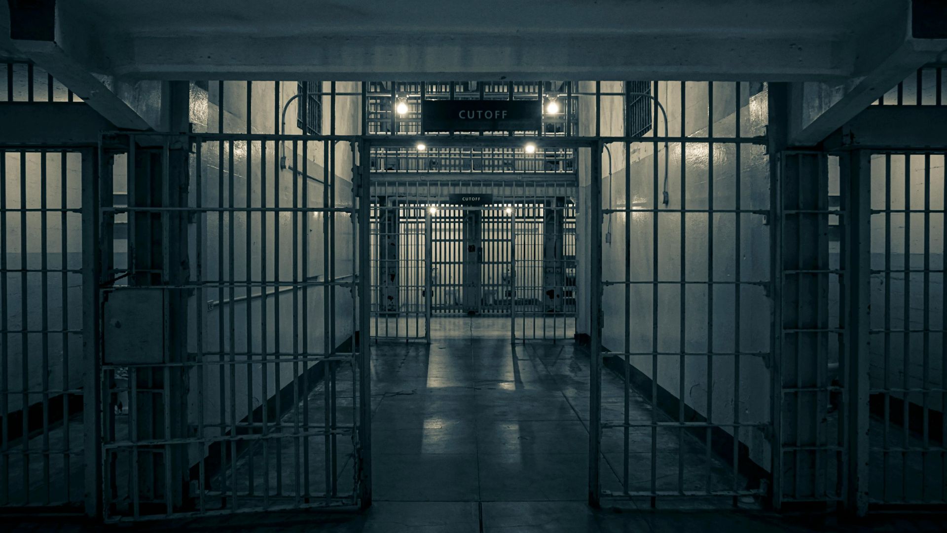 Moody interior of a prison corridor with metal bars, evoking a sense of confinement.