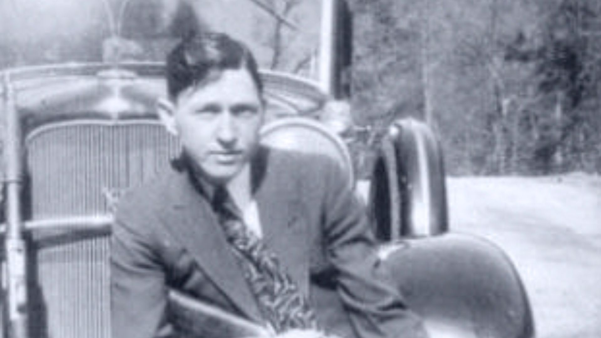 Clyde sat in his Ford V8 in a pose.