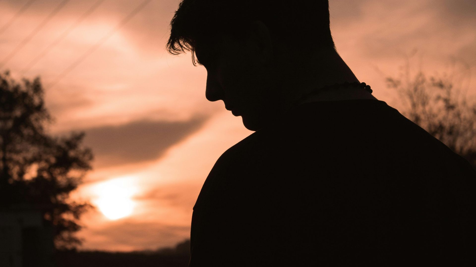 Silhouette of a young man standing against a vibrant sunset in Sakarya, Turkey.