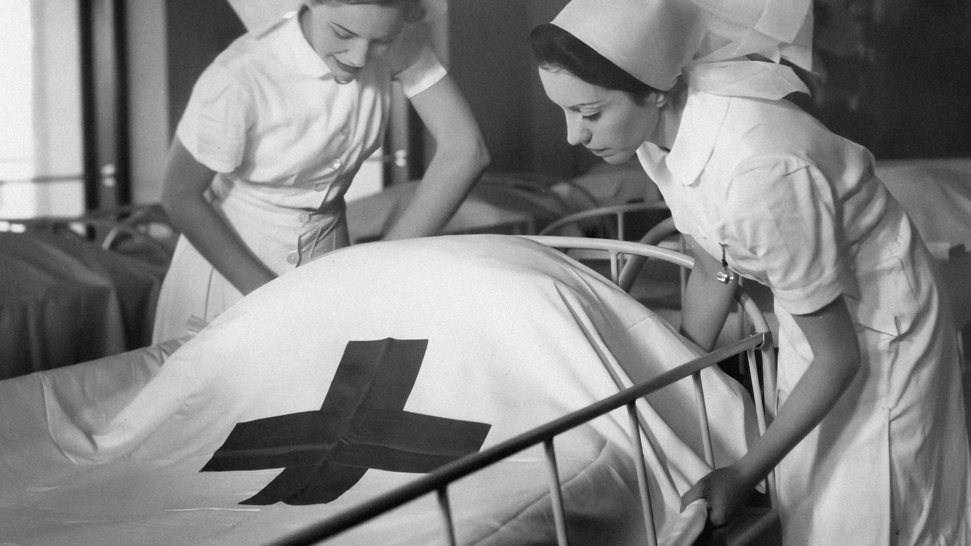 a couple of nurses standing over a bed